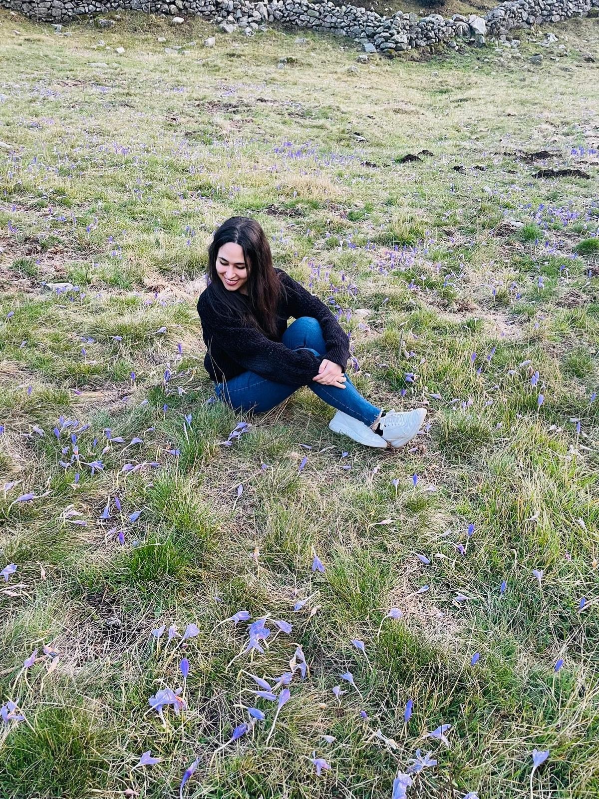 Clara Agnes outdoors in a green meadow, dressed in soft tones, looking calm and at ease in natural light